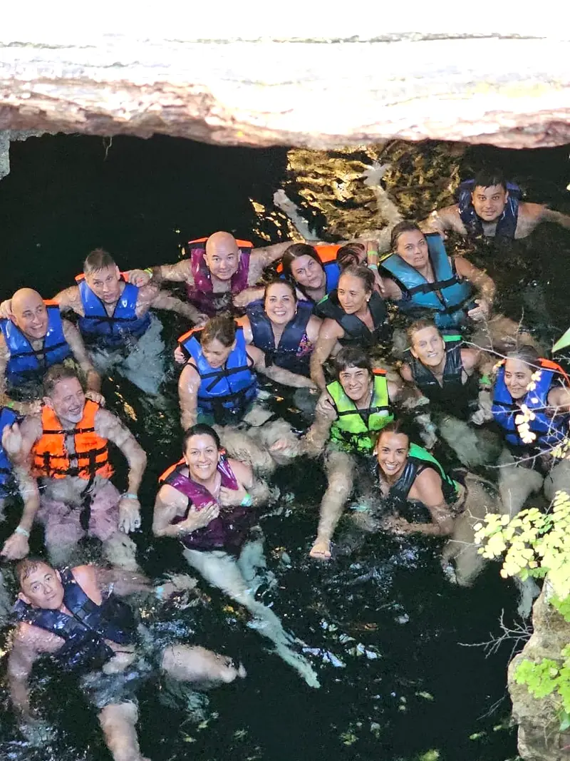 Grupo grande con chalecos salvavidas dentro del cenote